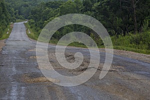 Very bad road in Russia. The asphalt road is all in holes in the middle of the forest.