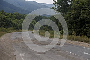 Very bad road in Russia. The asphalt road is all in holes in the middle of the forest.