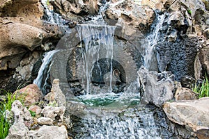 Very beautiful artificial waterfalls with living water and growing moss. Water flows from above, splashes and drops around