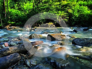 A very beautiful and natural view of the rapid flow of river water on large rocks in the wild forests of the mountains of Sumatra