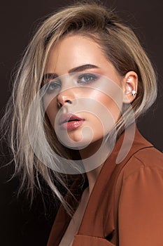 A very beautiful young blonde model with professional make up, perfect skin. Trendy red toned smokey eyes and nude lips.