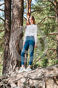 Very beautiful young woman in coniferous forest in summer in hot sunny weather