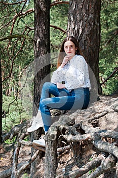 Very beautiful young woman in coniferous forest in summer in hot sunny weather