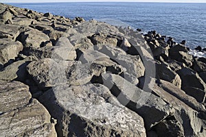 Very big and beautiful black rocks the power of the ocean gray lava stone close up grey rocks. Waves beat against the coastal sea