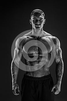 Bodybuilder posing. Fitness muscled man on dark background.