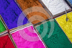 A very bright colored paint powders in a cardboard box with a spoon for the feast of Holy Diwali