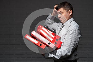 Very busy businessman closeup portrait, posing with red folders, overworking concept, dark wall background
