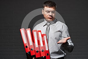 Very busy businessman closeup portrait, posing with red folders, overworking concept, dark wall background