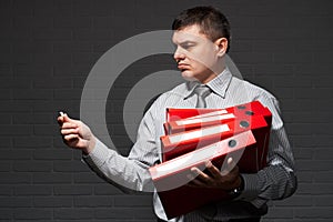 Very busy businessman closeup portrait, posing with red folders, overworking concept, dark wall background