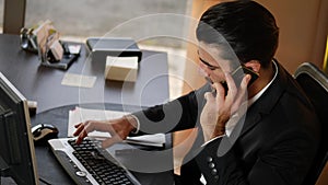Very busy businessman at desk on two phones