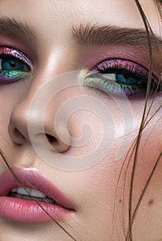 A very close up photo of young model with blue eyes, rainbow eyeshadows and perfect skin.