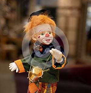 A very colorful clown doll with orange hair and a red nose