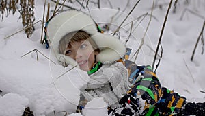 A very cute happy little boy in the Park in winter. Winter time. Happy boy having fun in a snow winter park. He is happy