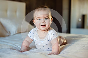 Very cute little baby boy lying on the bed on his tummy on a light veil