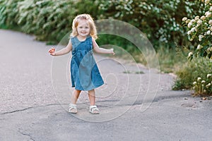 Very cute little girl with flowers in a denim sundress