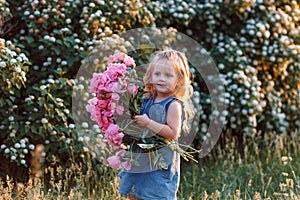 Very cute little girl with flowers in a denim sundress