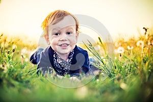 Very cute toddler smiling portrait in white dandelion meadow