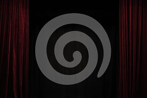 Very dark red velvet curtain on the sides of a black theatre stage, background frame with large copy space