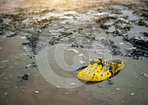 Very dirty yellow Shoe on the shore of a salt lake on a Sunny day