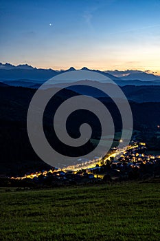 Very early morning shot of small village in front of high mountain range.