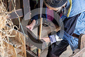 A very elderly undefined Hmong woman works on an ancient loom