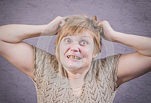 Very emotional angry woman with gold teeth on a gray background.