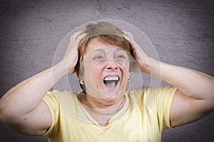 Very emotional woman screams in grief on a gray background