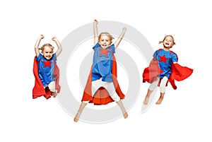 Very excited little girl dressed like hero jumping isolated on white background.