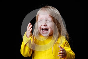 Very excited and screaming little girl in yellow, in dark room