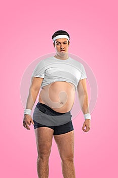 A funny fat man  on pink background. Obesity and eating disorder. Concept for dietetics and fitness advertising photo