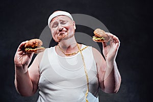 Very fat man with two hamburgers in his hands with his eyes closed