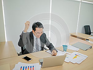 Very Happy asian business man sitting on his desk