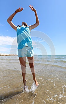 Happy little girl jumping with her arms up above the sea water i photo