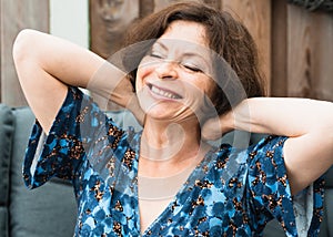 Very happy mature woman laughing, closing her eyes raising her hands