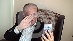 Very happy and smiling senior adult man with longing having a video call phone