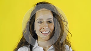 Very happy woman standing on yellow background and smiling