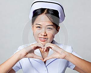 Very happy young Asian nurse show heart hand sign