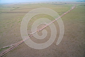 Very high aerial view of the Masaai Mara Reserve in Kenya during sunrise. Safari van drives on the dirt road