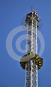 A very high merry-go-round at the Prater, the amusement park in Vienna, the people sitting on the seats descend in free fall downw