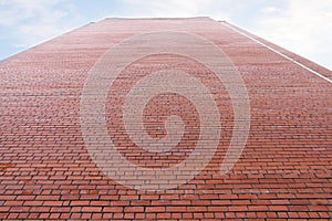 Very high wall of red brick building and cloudy sky photo