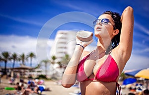 Very hot young woman holding coconut at the beach