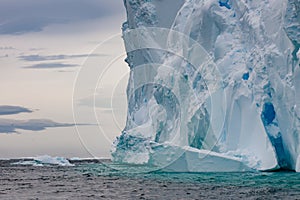 Very huge Iceberg with escarpment with reflections shining turquoise in Arctic water