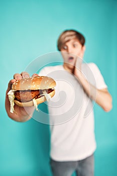 Very hungry young man holding tasty hamburger