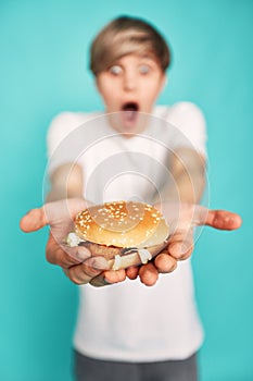 Very hungry young man holding tasty hamburger