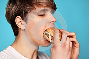 Very hungry young man holding tasty hamburger