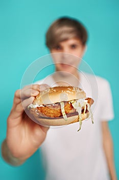 Very hungry young man holding tasty hamburger