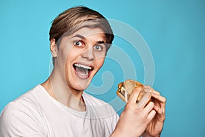 Very hungry young man holding tasty hamburger