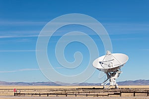 Very Large Array detail of radio antenna against a blue sky and distant mountains, listening to space