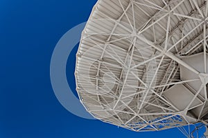 Very Large Array engineering understructure of a very large radio telescope dish against a vivid blue sky, copy space, science tec