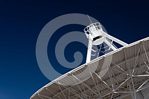 Very Large Array radio telescope pointing into space, white dish against a deep blue sky, space technology
